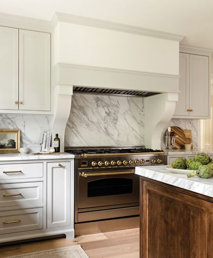 Natural wood cabinetry on the center island evokes a “found” furniture effect, adding a touch of masculine texture. The knotted, French Oak flooring grounds the light kitchen with a gracefully aged-in patina.