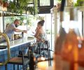 The bar is defined by a custom steel beverage rack packed with leafy plants and natural wine. “It was created to showcase the ever-changing wine list, and the plants add a lush layered look,” says Holly Freres.