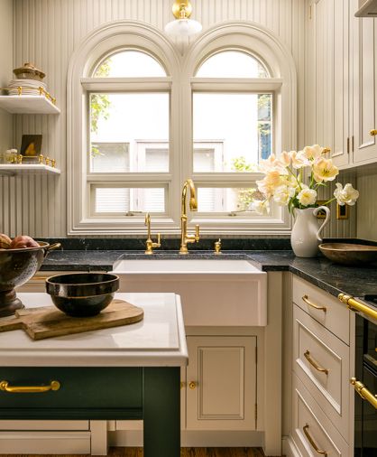 The functional kitchen looks traditional on the surface by obscuring modern appliances behind the cabinetry and featuring enduring materials like unlacquered brass from Rejuvenation and natural granite. The lighting is from Schoolhouse Electric. The Newport brass faucet and Barclay sink are from Fergusons.