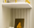 Centering the large farmhouse sink to the windows created some asymmetry, solved by adding brass-accented decorative shelves.