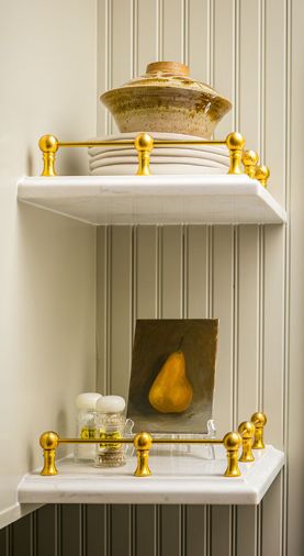 Centering the large farmhouse sink to the windows created some asymmetry, solved by adding brass-accented decorative shelves.