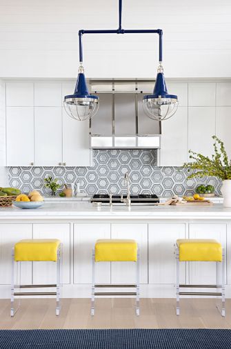 A pop of yellow from Lee Industries stools from J Garner Home. Architectural Stonewerks island counter fabrication with Ann Sacks backsplash and Urban Electric Co. pendants. Studio AM Architects & Interiors designed a new range hood and replicated existing cabinets in the island unit.