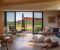 Integrated glass sliders from Portland Millwork open the indoor living to the outdoor patio. The primary living area is outfitted with an Emmy Sofa in Walnut & Cinder Pebble Weave, a Paulistano Armchair, Herman Miller Eames chair and a custom table by Fallen Industry.