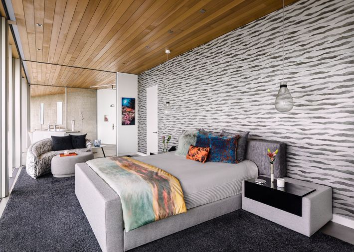 The primary suite designed by DOMOV I.D., with Romo wallcovering mimicking ocean waves and coverlet echoing sunset. Poltrona Frau (Italia) pendant lights over the Vioski custom Zurich bed. Ann Gish coverlet teams with Drainsfield & Ross accent pillows.
Photo by Justin Krug