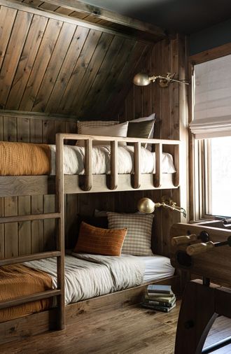 In the wood-paneled bunk room, the custom bed frames are designed by Jessica Nelson and fabricated by WoodRidge Custom Homes. Each bunk is provided with ample reading opportunities with brass bedside lighting from Etsy.com. The engineered hardwood flooring throughout is from MB Designs.
