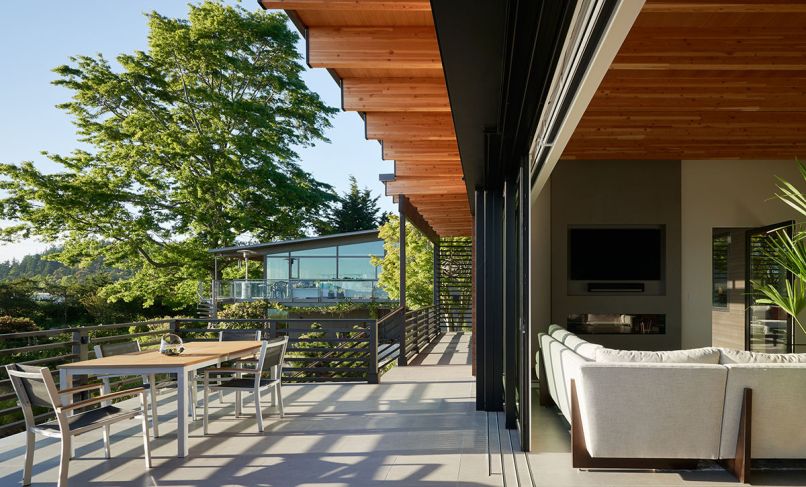 A Weiland 32-foot lift and slide door by Andersen connects the living spaces to the exterior deck, as does the seamless porcelain floor covering. The lumber throughout was provided by Lindal Cedar Homes, while the exterior dining table was built by Schaefer Construction.