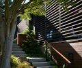 A slat wall, designed by OTO Design with lumber from Lindal Cedar Homes, divides the protected covered porch from stairs leading to the landscape and beach.