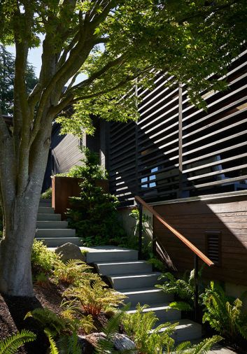 A slat wall, designed by OTO Design with lumber from Lindal Cedar Homes, divides the protected covered porch from stairs leading to the landscape and beach.