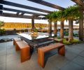 In the outdoor dining room, four columns border a patio composed of Vancouver Bay Architectural Slabs from Mutual Materials. Jane Friedman made the custom glass table from an old factory cart.