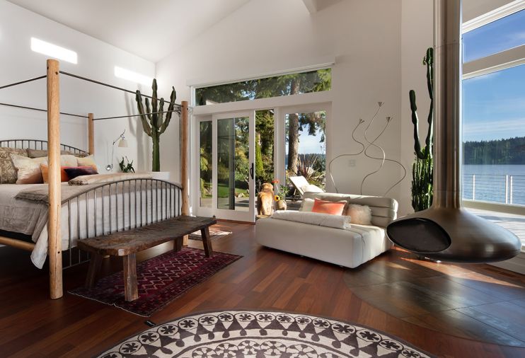 The primary suite has a private deck and views, as well as a suspended Gyrofocus fireplace from Focus. A Nanimarquina Rangoli rug centers the room. A vintage work bench from Obsolete, bedside lighting from DWR and vintage Turkish rug bring in texture and light.