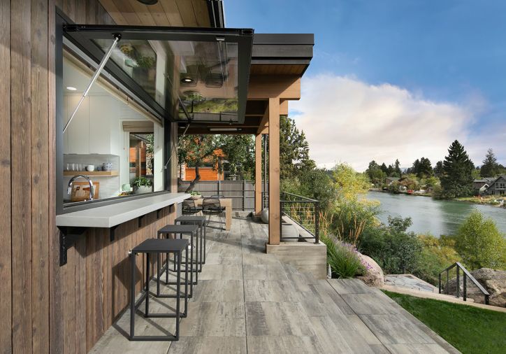 An awning window with gas struts from Central Glass & Aluminum in Australia opens to an exterior concrete serving and dining counter, fabricated by local company Cement Elegance. The stools are from Terra Outdoor Living.