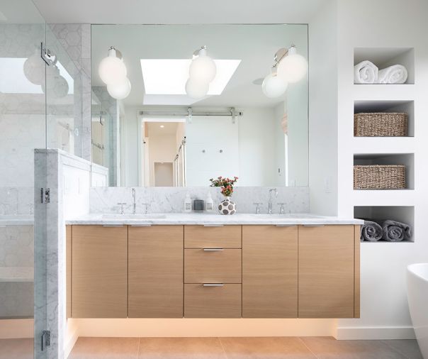 In the bathroom, the white oak vanity is topped with a Carrara marble, and has Kohler plumbing and Rejuvenation sconces.