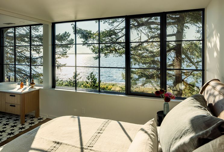 The main bedroom can be fully opened to the ensuite via a sliding door. Traditional paned glazing on the upper floor provides privacy while tempering the home’s modern silhouette. The bathroom tile is Stella Nero Encaustic star tile from Merola.