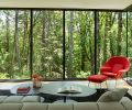 The cantilevered living spaces combined with floor-to-ceiling glass make the interior feel suspended in the forest.