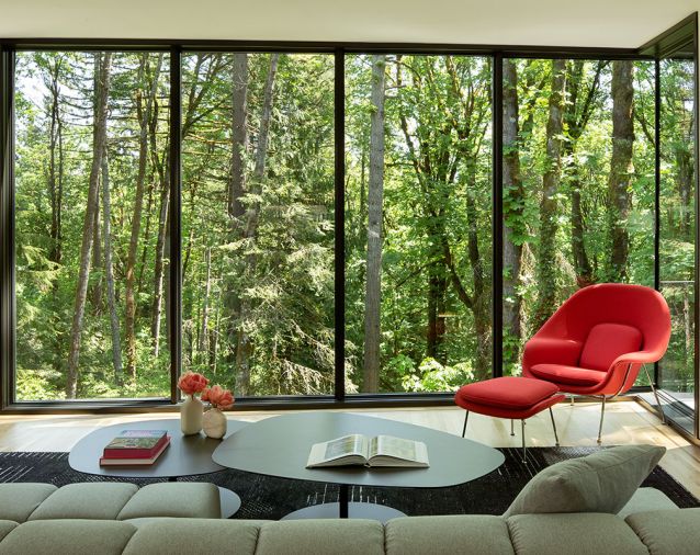 The cantilevered living spaces combined with floor-to-ceiling glass make the interior feel suspended in the forest.