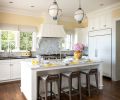 The custom Hull pendants from Urban Electric Company and Mattaliano Fente counter stools from Terris Draheim pair with existing white oak flooring. Benjamin Moore Simply White trim with Calming Cream walls complement the Sub-Zero refrigerator and Wolf range.