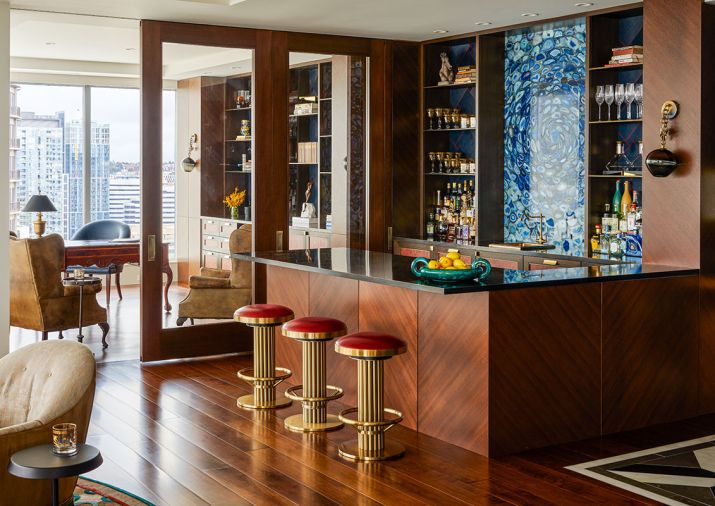 Art Deco stools from J Garner Home by J. Alexander face The Stone Collection’s backlit Blue Agate Slab. Harriet Industries antiqued brass countertops and shelves. Custom door and Fumed Oak casework with Brass Metal Screed details and leather panels by Stusser Woodworks.