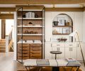 Initially surrounded by craftsman-esque built-ins, this area of the great room felt heavy and uninviting. Scherie replaced them with custom cabinetry by DMC Cabinets, including an arched vestibule and glass-fronted shelving matching the kitchen.