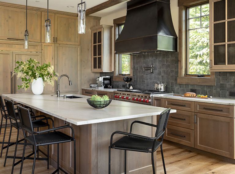 In the kitchen, RH Machinist Cylinder Glass Pendants hang above the substantial island, topped with an Adacia Quartzite Honed countertop from Stonewood Design. The clear and knotty Alder cabinetry throughout is from Sky River Industries.