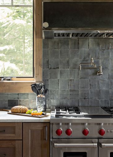 For the kitchen backsplash, Stonewood Design installed Enzo Graphite Nakama Field Tile from United Tile. The 48' gas range is by Wolf, while the Monsoon hood insert is by Zephyr.