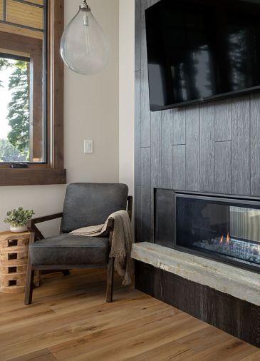 The bedroom fireplace has a Quartzite natural rock ledge from Marenakos and Millennial Ebony porcelain tile by Architectural Surfaces.