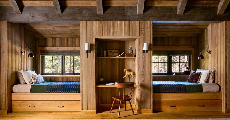 “The bunk room was all basically custom hand built with our finish carpenter,” says Redding. Rustic red cedar casework is by Beamworks, in Oyster Bay color. The sconces flanking the desk are from Pottery Barn, and the bunk lighting from Schoolhouse.