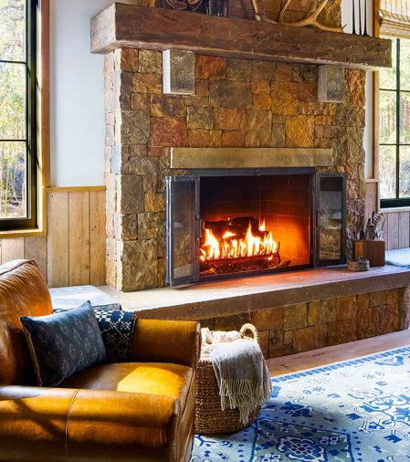 An original Lancaster Leather Chair from RH is a cozy spot by the fireplace.
