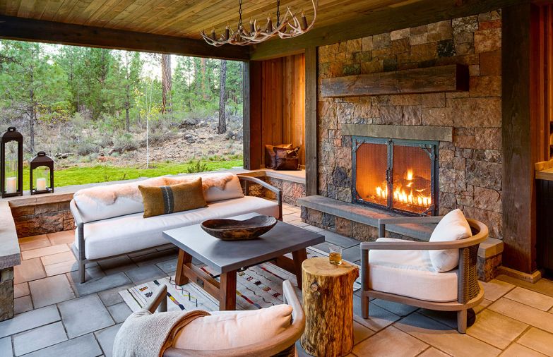 The protected back patio has a fireplace with a stone surround and hearth from Select Stone, and custom ironwork. The chairs and sofa from RH are paired with a custom antler light from Crooked Creek, and a handmade, hand-dyed wool rug from the Tallerocho8 workshop in Teotitlán del Valle, Mexico.