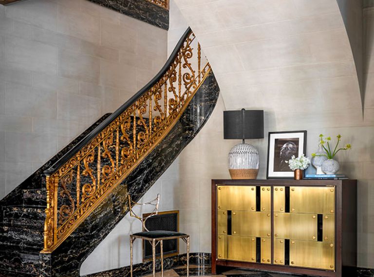 Missing c. 1922 bronze “S” railing was recast for Potoro marble staircase. Dingy walls refreshed with limewash plaster by Studio C. Stunning brass Necchi sideboard from Natasha Baradaran. Uteki painted lamp from Anthropologie and bronze Amsterdam Chair from Magni Home Collection.