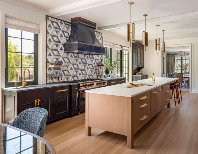 Bleached walnut cabinetry from Northwest Custom Interiors face off with Eurocraft Hardwood Floors. Liaison Doheny KW tile backsplash by Ann Sacks with Statuario Maxim soapstone counter, both from Grandy Marble & Tile. Miele dishwasher, Bluestar range and Zephyr hood insert inside a Decorative Metal Arts hood. Circuit Virtual task lighting from Apparatus.