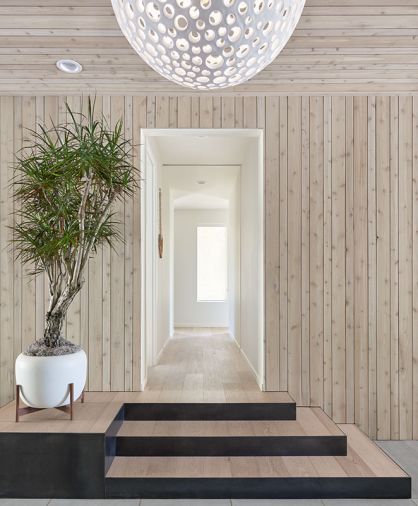 In the entry, the tongue-and-groove wood is brought inside for consistency. On the floor, Stepstone Inc concrete pavers from Willamette Graystone and Oly Studio Annika lighting.