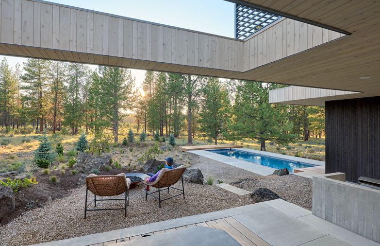 In lounge located in the back of the house, a cut-out in the roof allows stargazing from the custom hot tub. The in-ground pool is custom built with a retracting safety cover and black brick coping, by SPS Specialized Pool Services.