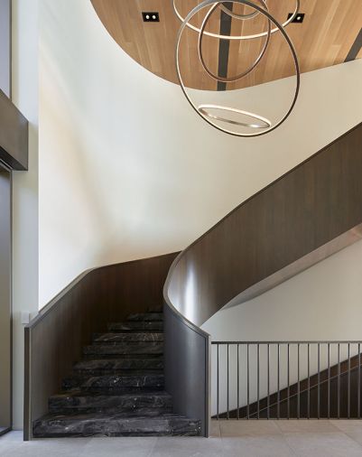 The stunning staircase handcrafted onsite by Beautiful Custom Stairs, features Arabescato Black stone treads from Architectural Stone Werkes and a Twisted Metalworks steel bar rail.