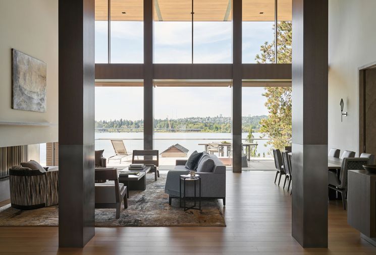 The great room offers Joseph Jeup Riparo chairs with Holly Hunt leather and Great Plains upholstery on a Holly Hunt sofa, both from Jennifer West Showroom. The two-story glass wall with electric doors is by Sky-Frame, and the elegant Tufenkian carpet is from Driscoll Robbins Fine Carpets.