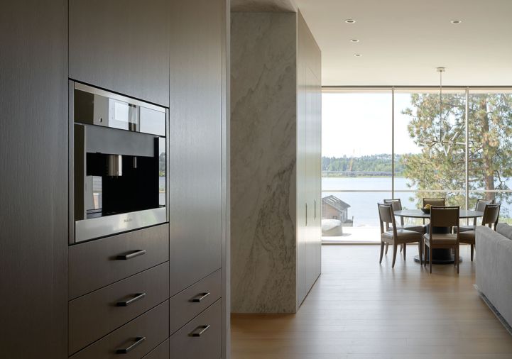 Rift and quartered white oak flooring with custom stain throughout by Eurocraft Hardwood Floors, LLC. Hidden workspace and chair are tucked behind pocket doors beyond the Bianco Mundra Quartzite from Architectural Stone Werkes.