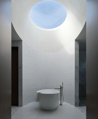 The primary bath’s oculus window highlights the very private radius wall trimmed in tiny Carrara marble tiles from Statements Tile & Stone. The elliptical Olivia 2 MTI tub reiterates window style above, with a Rettanglo tub filler by Gessi.