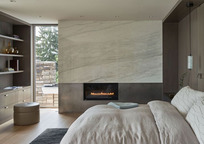 A Calacatta Caldia marble crowns the Montigo fireplace from Thompson Home and Hearth and teams with a custom ottoman from Village Interiors. The Arris Tub Bed is from Kelly Forslund with an Altura Wood Bed Frame.