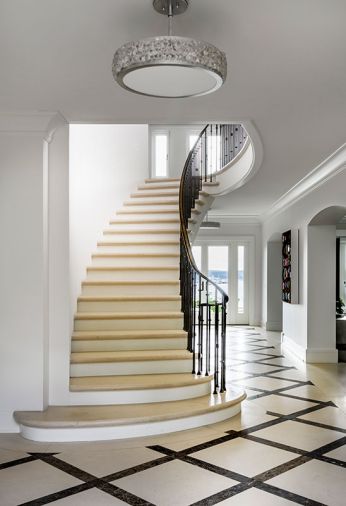 In the entry, the existing floor and staircase were maintained, and an Arctic Halo from Fine Art Handcrafted Lighting added. The Sprunks “wanted to ‘Sprunkify’ the home and make it their own,” says contractor Pete Lacic. Benjamin Moore “White Dove” paint was applied throughout.