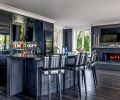 The entertainer’s zone has custom, paint-grade cabinetry from Interior Environments at the bar, with a leathered Absolute Black granite counter and Imperial Duchess Mirrored Tiles from Bedrosians Tile & Stone. Custom designed fireplace by Ronda Divers Interiors.