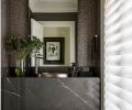 In the powder room, a waterfall slab of Astoria Skys from Elemar and a Hibiscus Hammered Nickel sink by Native Trails from Seattle Interiors, forms the floating vanity. The wallcovering is Granite II from Phillip Jeffries.
