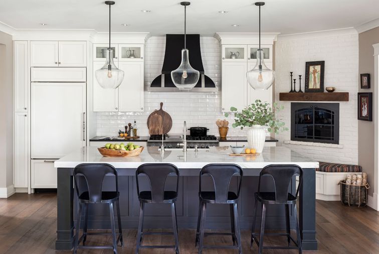 The kitchen has a timeless feel with classic colors of warm, creamy white and matte black accents. It is an inviting backdrop to showcase the homeowners’ collections from a life of world travel. The custom cabinetry by Aura Cabinetry includes multiple glass-fronted options to showcase special items. The appliance package is from Eastbank Contractor Appliances and the Walker Zanger Cafe ceramic subway tile backsplash from Paulson’s Floor Coverings adds classic charm to the space.