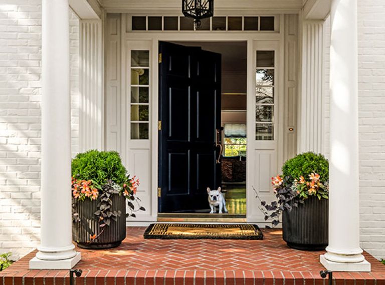 Maison, Inc.’s classic Colonial style new door with sidelights along with the family’s French Bulldog pup welcome visitors.