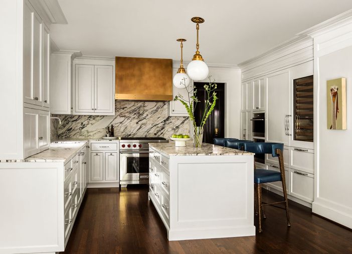 All traces of a hulking 90s kitchen remodel disappeared in this elegant down-to-the-studs new kitchen that boasts Wolf, Sub-Zero, and Miele appliances from Eastbank Contractor Appliances. A stunning Schmeer Brass range hood pairs with Eddystone Pendants highlighting Calacatta Viola marble backsplash and new island countertop.