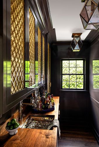 A former ugly duckling butler’s pantry now packs a sexy punch that invites bartenders to tarry awhile amidst the yummy surroundings. The solid walnut counter adds ballast to the lacquered cabinetry by Eddie Murphy Cabinets beneath showy Kardamyli Ceiling Lights.