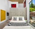 In the primary bedroom, the bed and side tables are from Roche Bobois, and large windows make it so the room shares in the view. The yellow artwork is by George Vergette, and the red and black piece from Lucas Wolf, both Vancouver, B.C. artists.