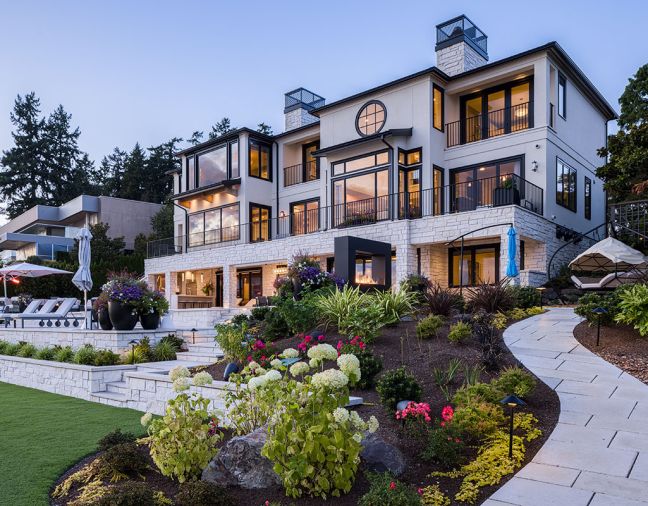 The inspiration to update the exterior using stone pavers from the Dordogne region of France led to facing the terrace with Antique Pearl Merrillstone. Kolbe Windows and Nana Doors, and a custom KODO Unit from Fireside Home Solutions add panache. Lush landscaping by Kenneth Philp Landscape Architects.