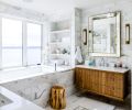 Large Kohler Underscore Rectangle tub is faced with Walker Zanger Studio Moderne™ Calacatta honed from United Tile. Keely Tall Pivoting sconces trimmed in hand-rubbed antique brass are grounded by warm Winterwood Custom vanity. Organic White counter from Caesarstone.