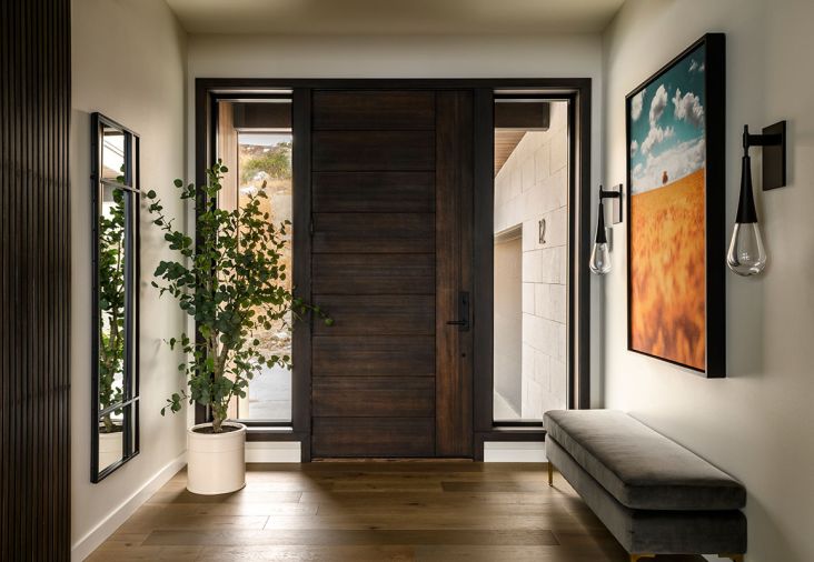 Welcoming guests, Hammerton Studio sconces flank a painting that recalls local trees in autumn and large windows throughout offer views of inspiration. The interior designer pulled in many elements of the natural environment into the design