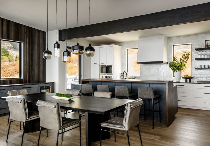 The dining room’s wood accent wall ties with the library wall paneling. The classic look of a table built by Smith Custom Woodworking sync with the kitchen’s Chloe tile backsplash and blue hues in the Ijen Blue Quarzite counters