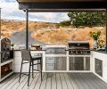 ABOVE The outdoor kitchen is well-equipped, complete with a Tuscan Chef wood-fired pizza oven, Le Griddle, and Blaze Grill, all from from BBQGuys. A granite counter surrounds an Elkay sink and Lynx Grills faucet from Ferguson